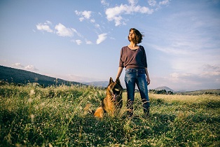 A woman and her shepherd dog in an open field