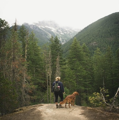 A hiker and her dog enjoys the view from the mountaintop